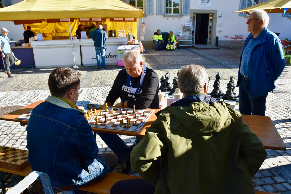 Eine Runde Schach vor der Oberen Mühle: Diese Besucher nahmen es am Samstag bei der Einweihung des Speichers gemütlich. Drei Männer sitzen an einem Tisch und spielen Schach.